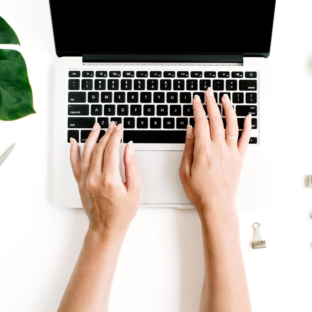 hands typing on a laptop keyboard
